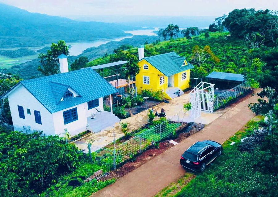 Hai căn nhà trắng và vàng trên đồi cà phê, xa xa là hồ Tà Đùng